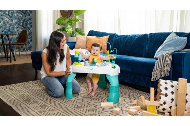 toddler in activity center with mother by his side