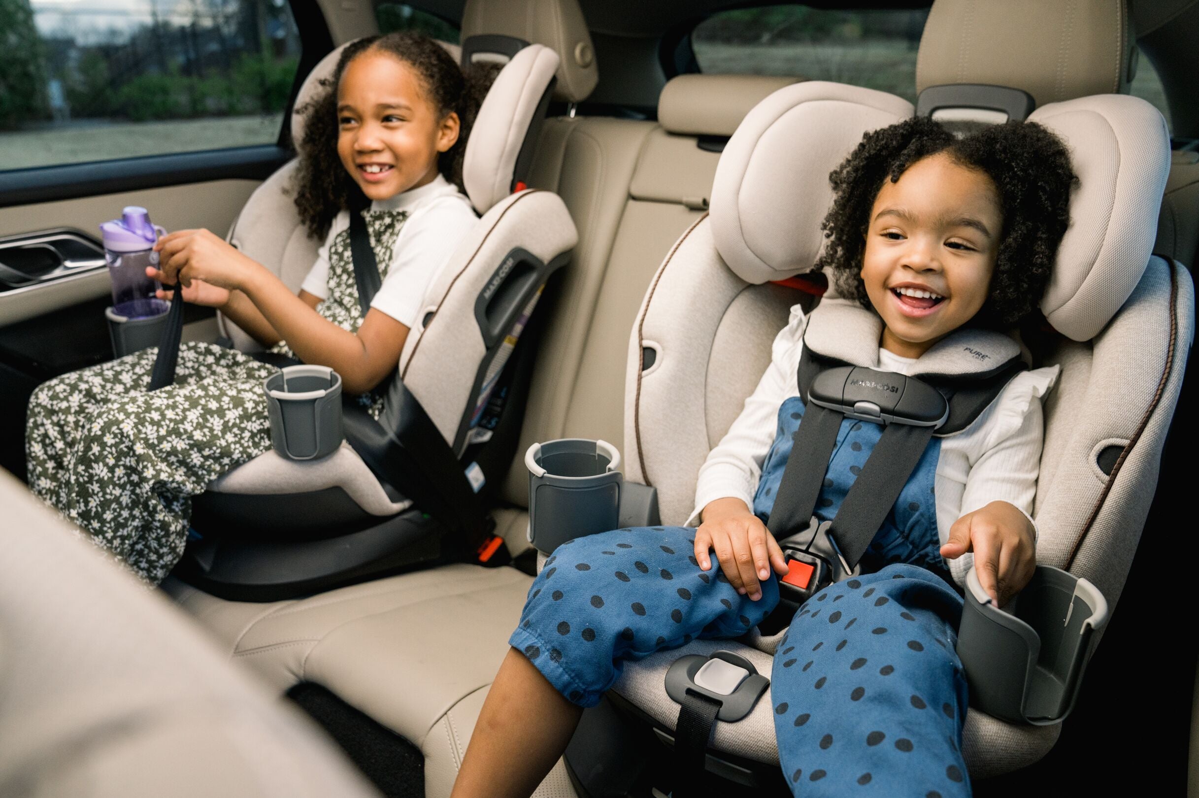 two children smiling in car seats