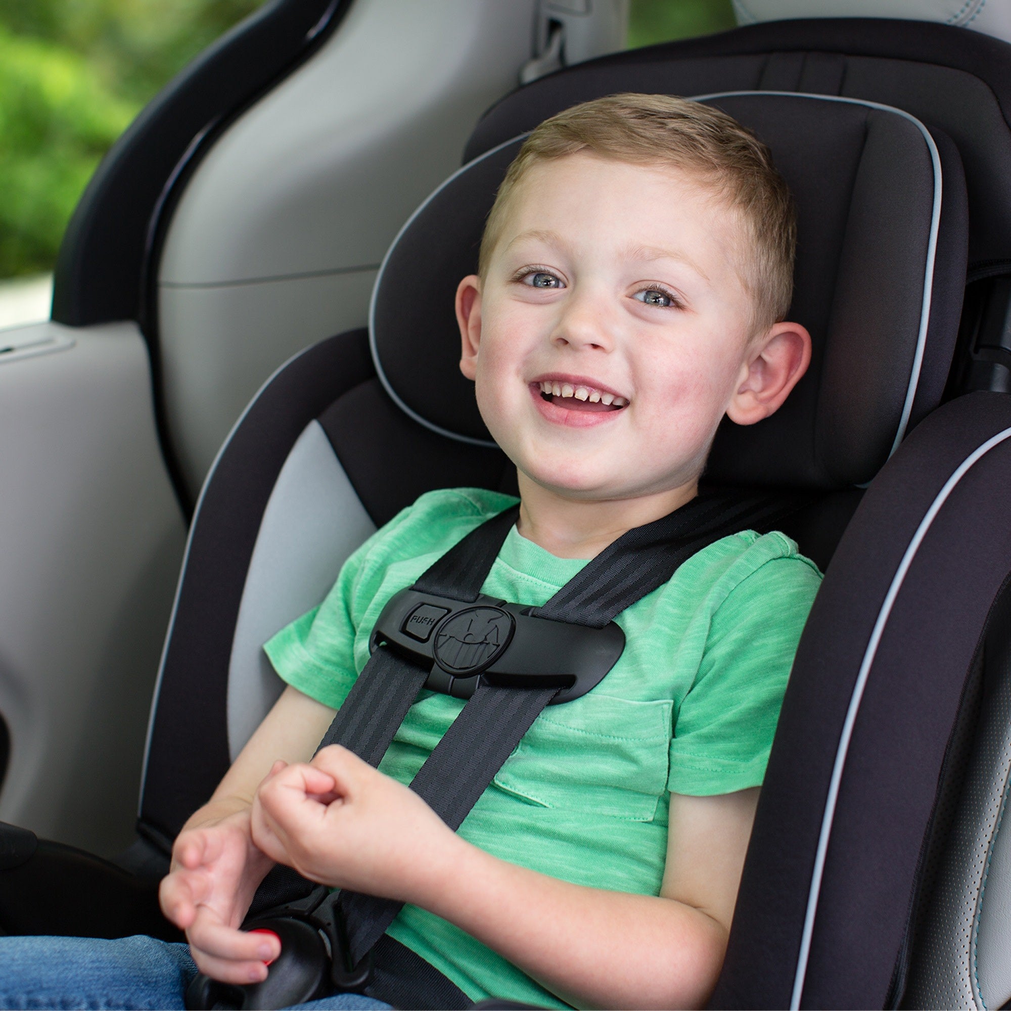 toddler boy in green shirt sitting in harness booster car seat
