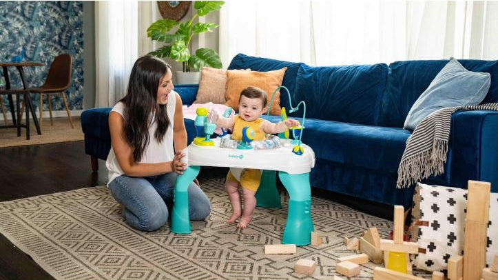 toddler in activity center with mother by his side