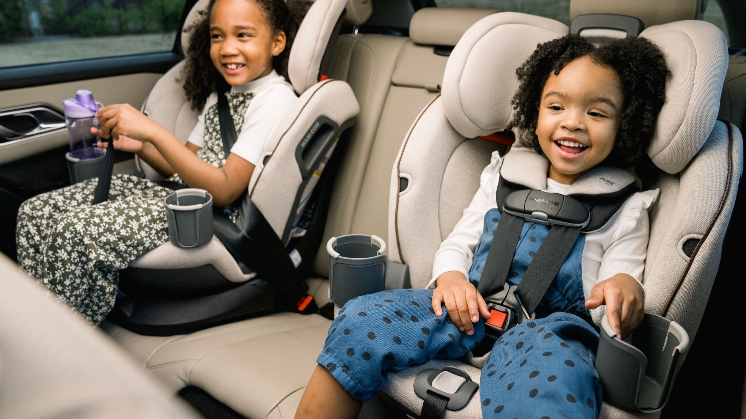 two children smiling in car seats