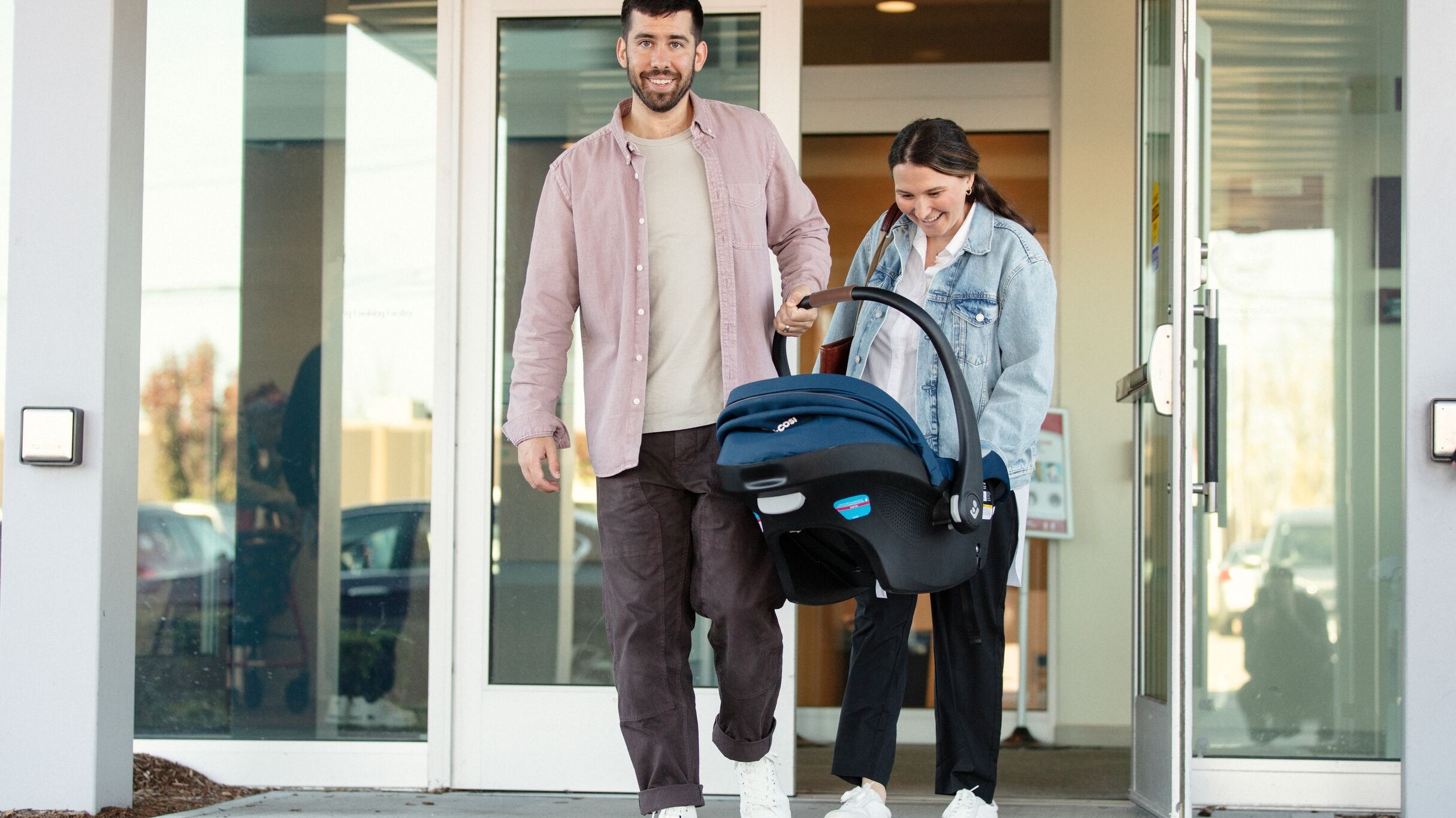 mother and father carrying infant car seat