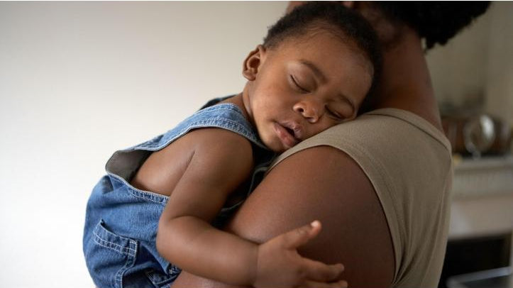 mother holding sleeping toddler in her arms