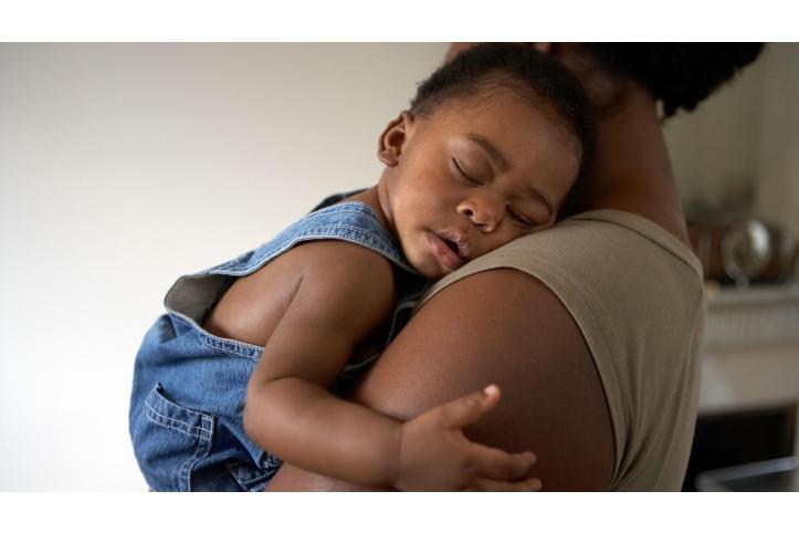 mother holding sleeping toddler in her arms