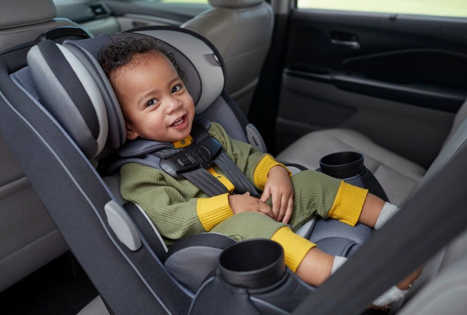 toddler in car seat looking at camera smiling
