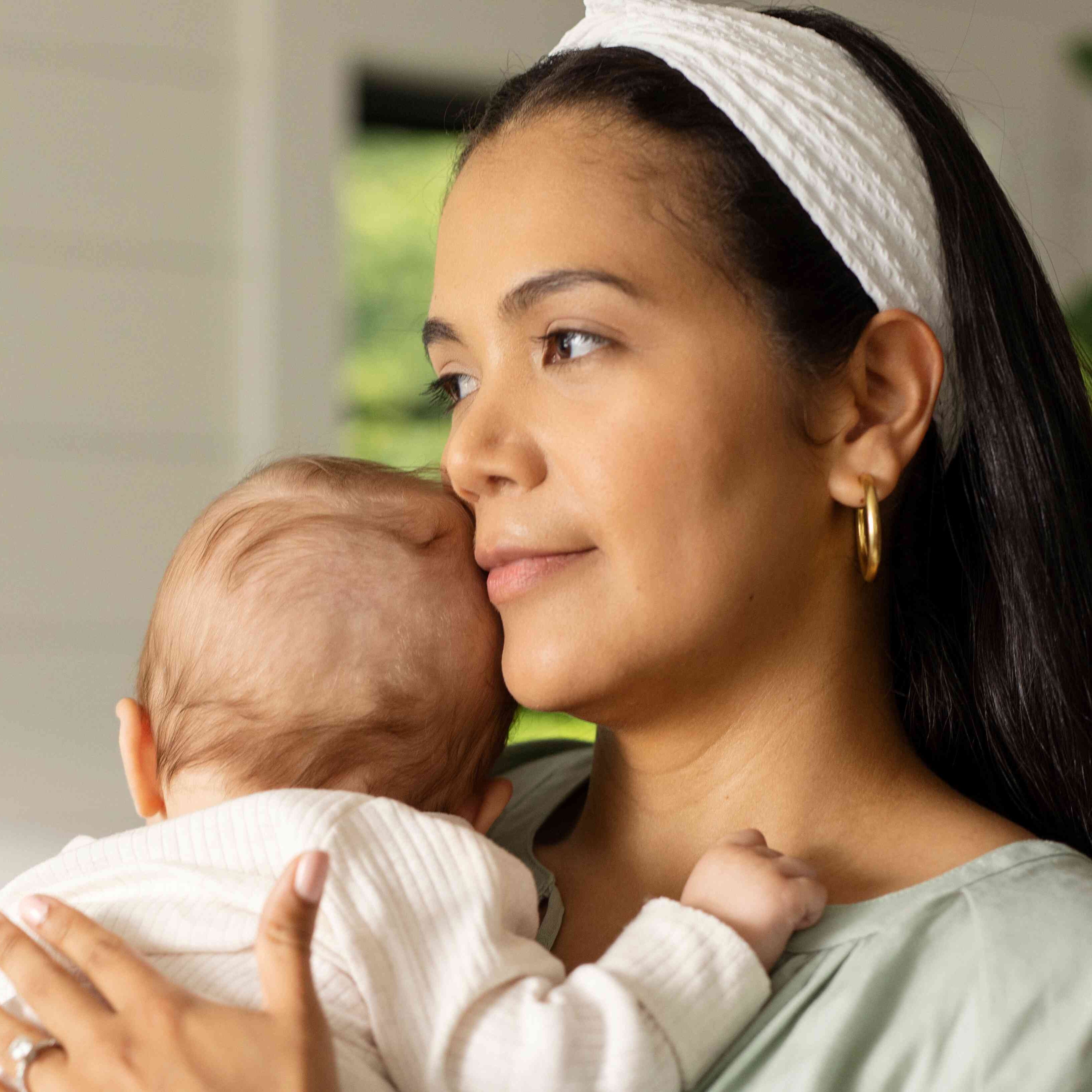 smiling woman wearing white headband holding baby