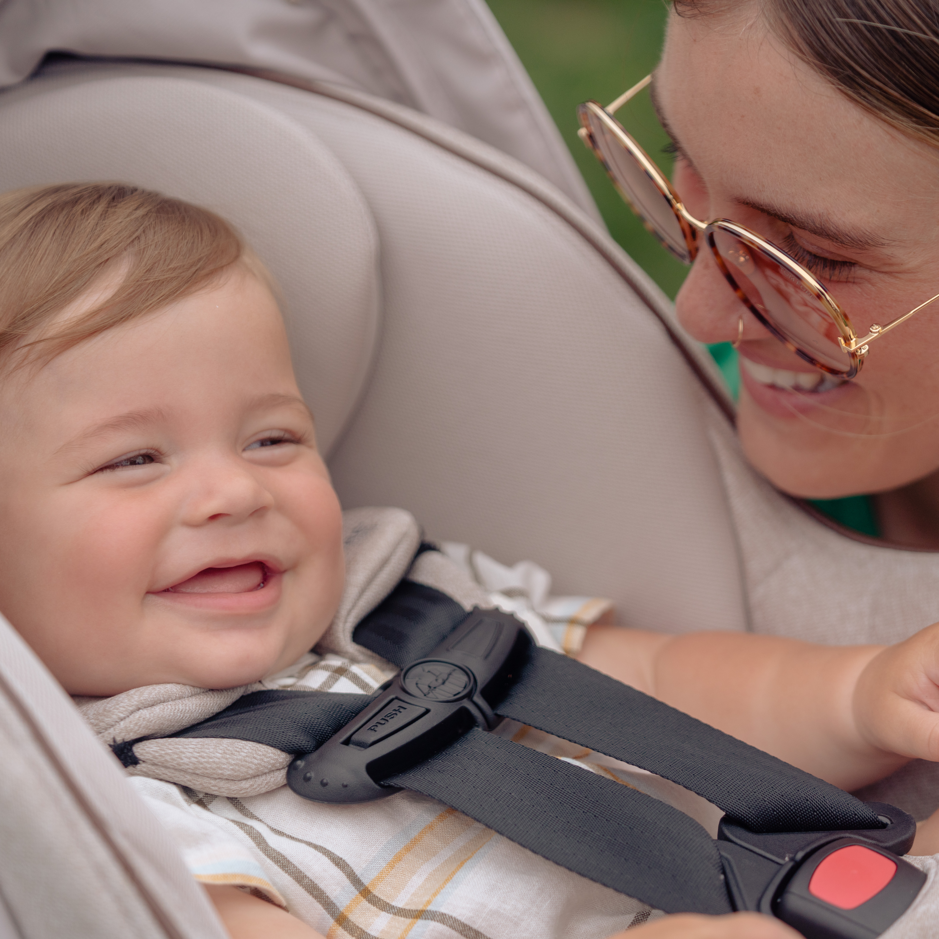 mom smiling at smiling baby in infant car seat