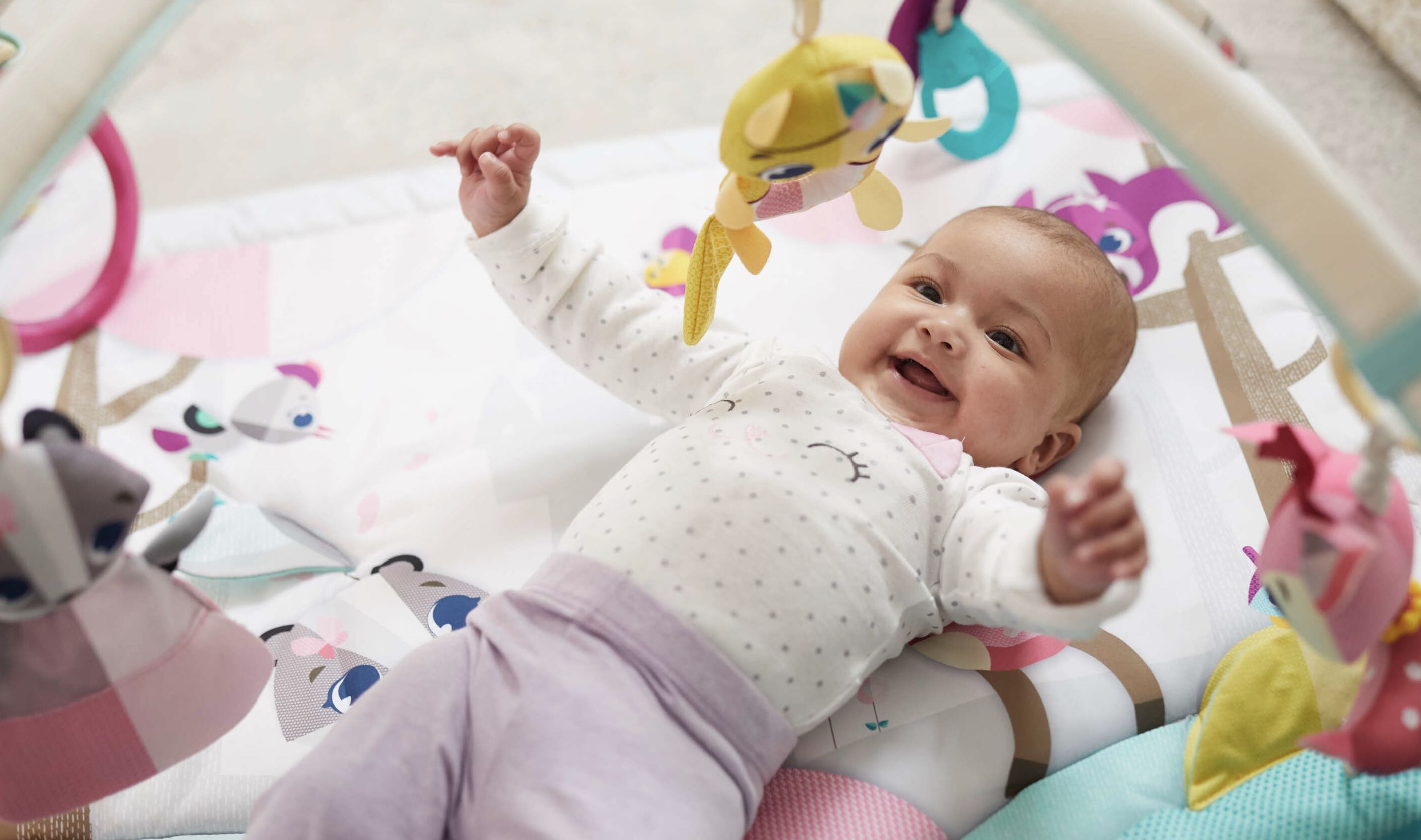 baby laying on play mat smiling
