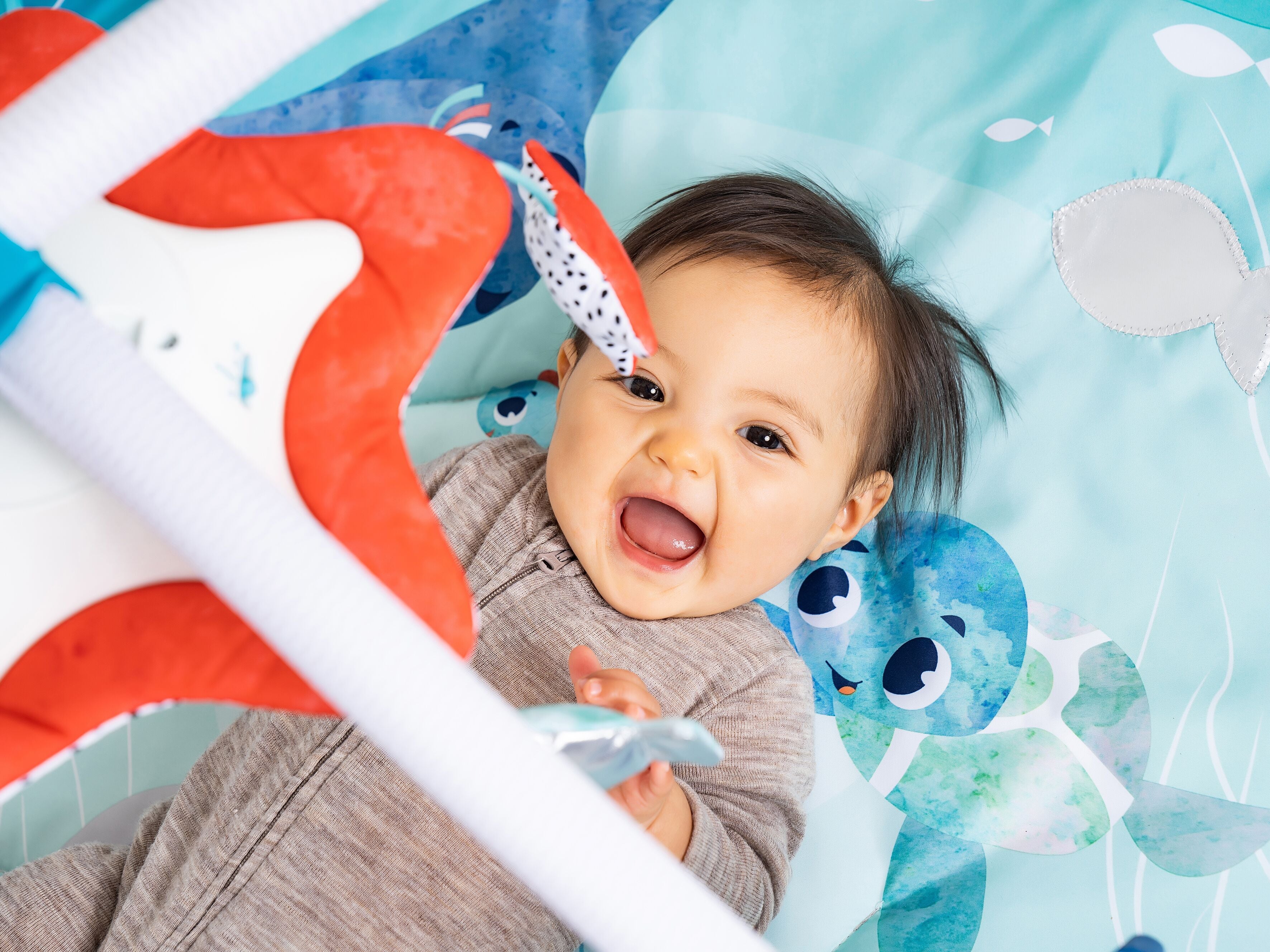 baby laying on back on play mat smiling