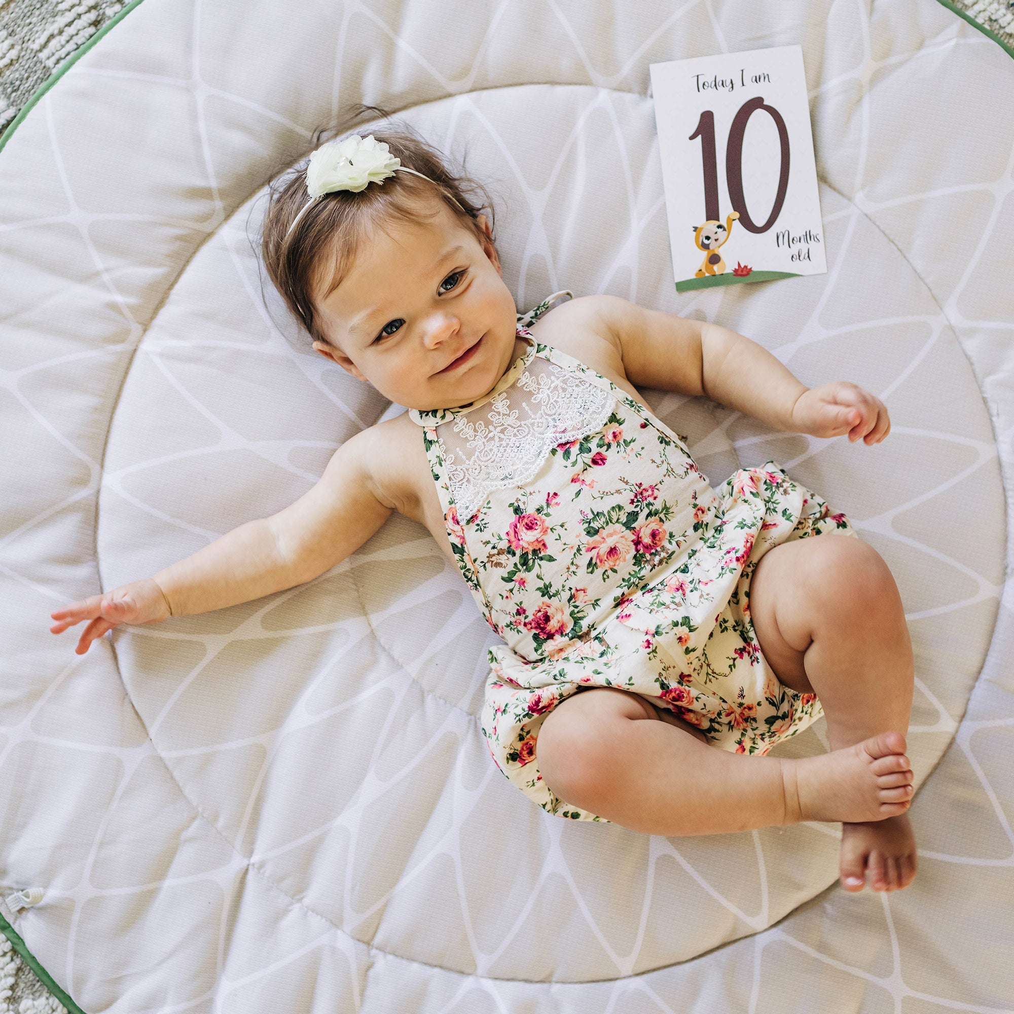 Tiny Love Luxe Developmental Gymini - baby on back on mat with card next to her that reads, "today I am 10"