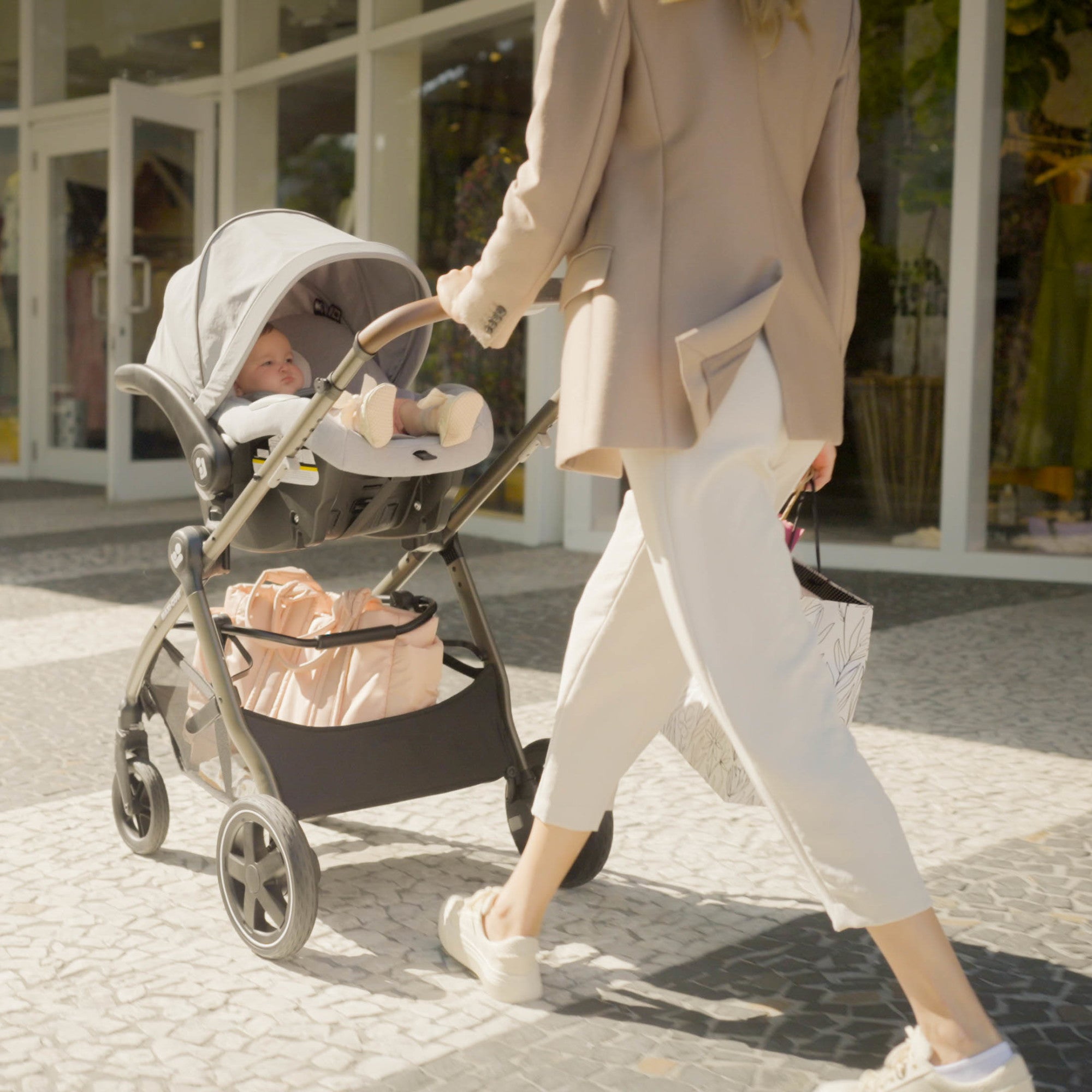 Zelia™² Luxe 5-in-1 Modular Travel System - mother walking baby in rear-facing stroller mode