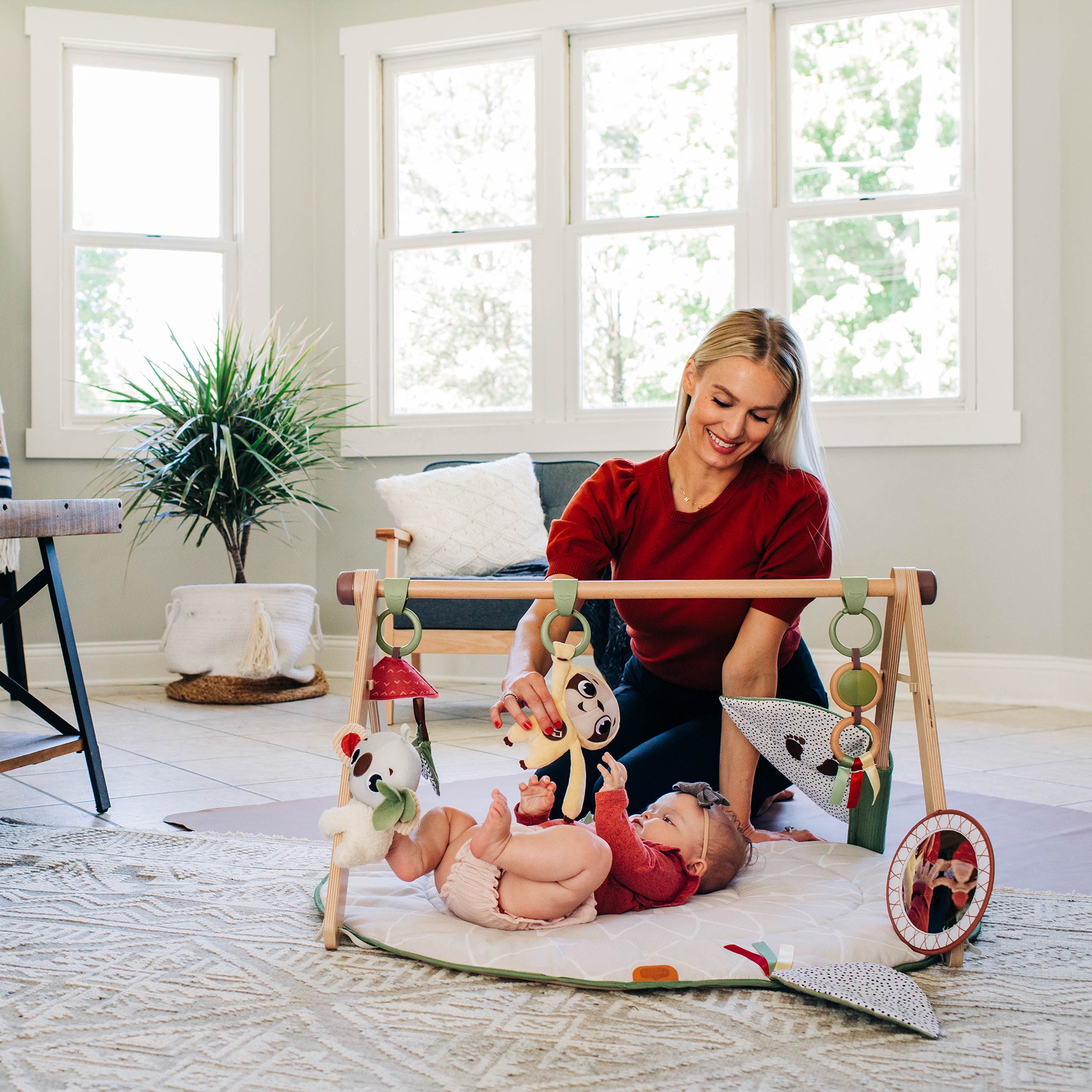 Tiny Love Luxe Developmental Gymini - mother playing with baby who lies on back on mat playing with toys
